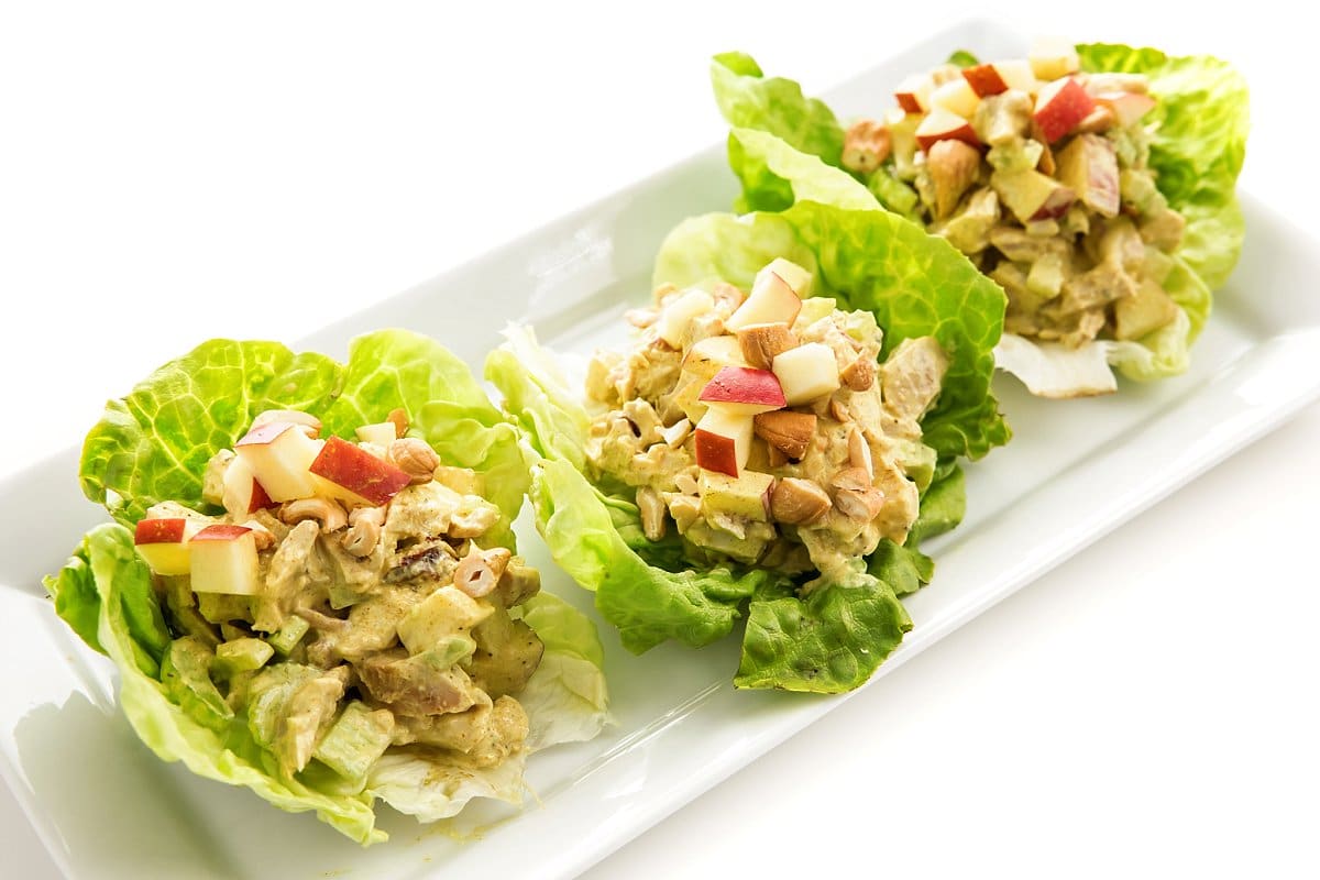 Three lettuce cups full of curried chicken salad with apples.