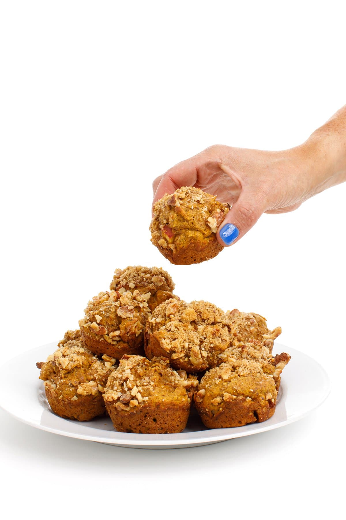 A hand grabbing a pumpkin applesauce ،in from a stack with a white background