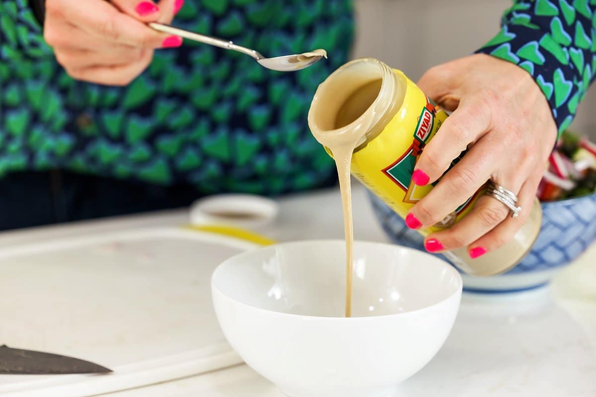 adding tahini into a bowl