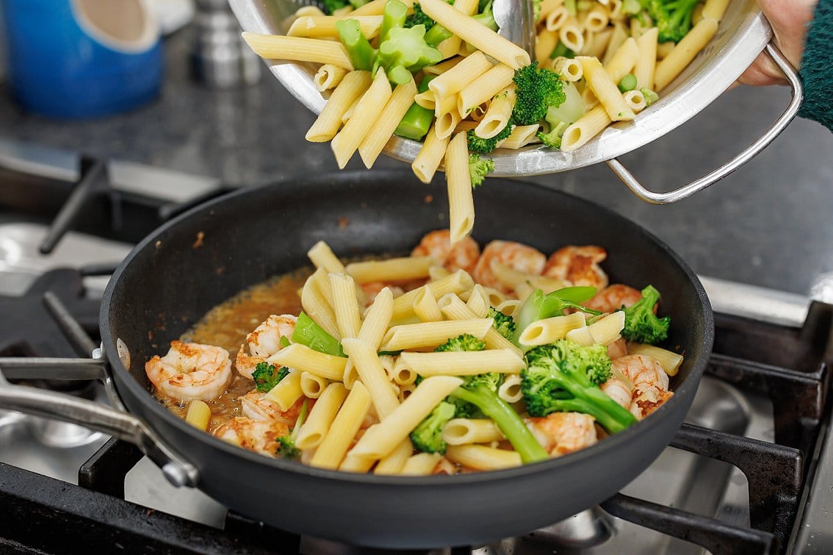 Adding pasta and broccoli to shrimp