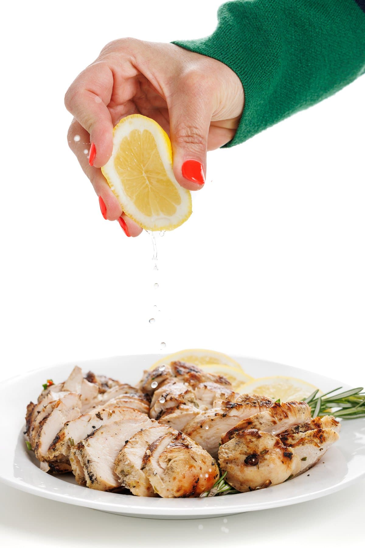 Garnishing rosemary chicken breasts.