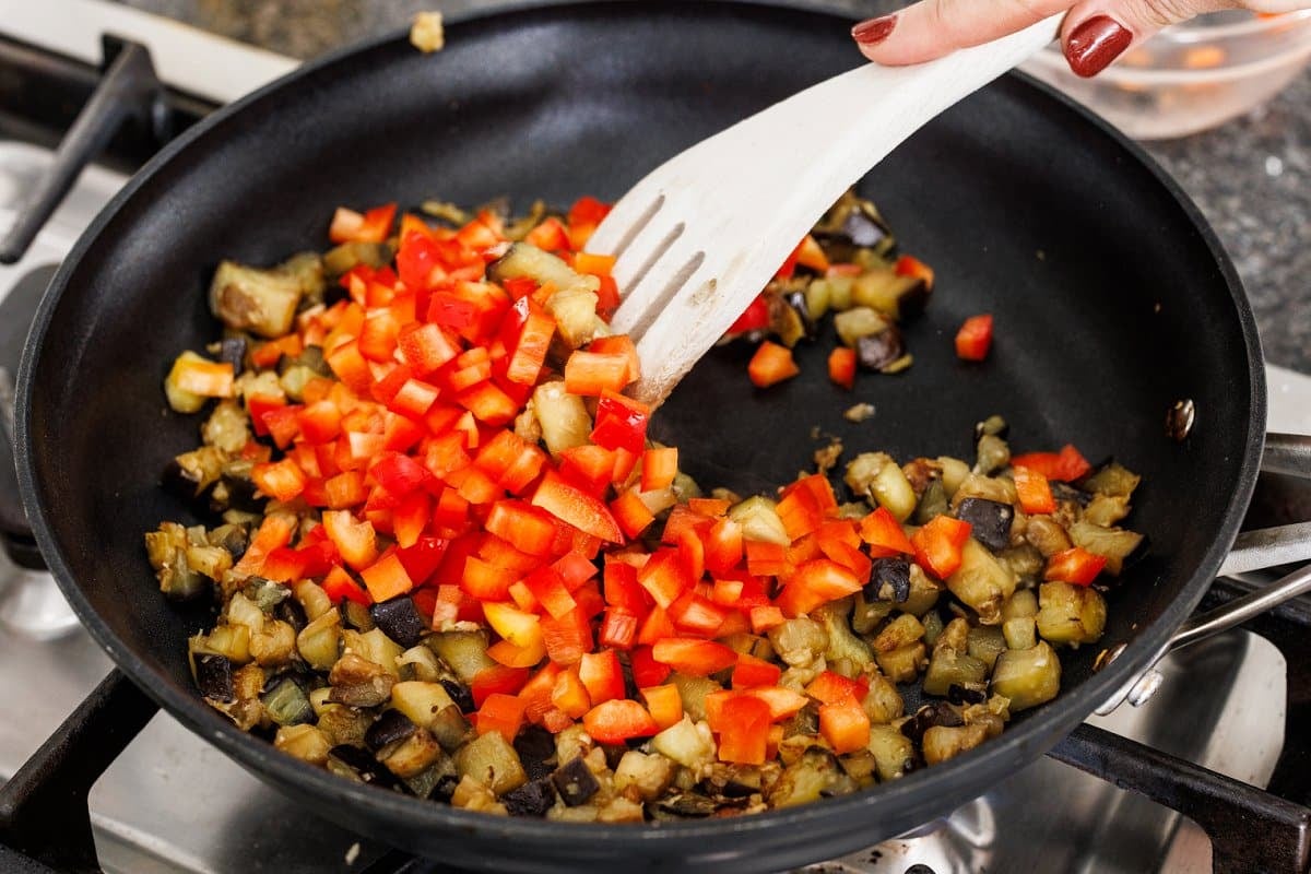 Adding diced red bell pepper to pan