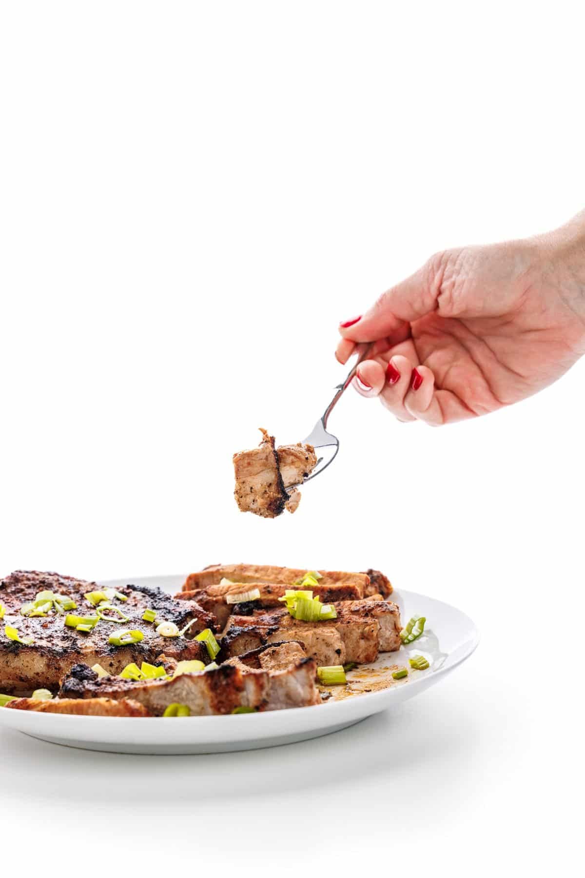 Forkful of smoky grilled pork chops.