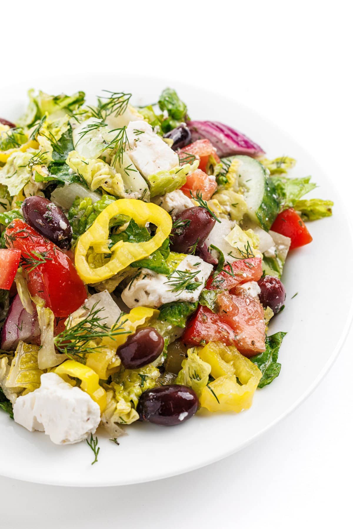 Traditional Greek salad on a white plate with fresh dill.