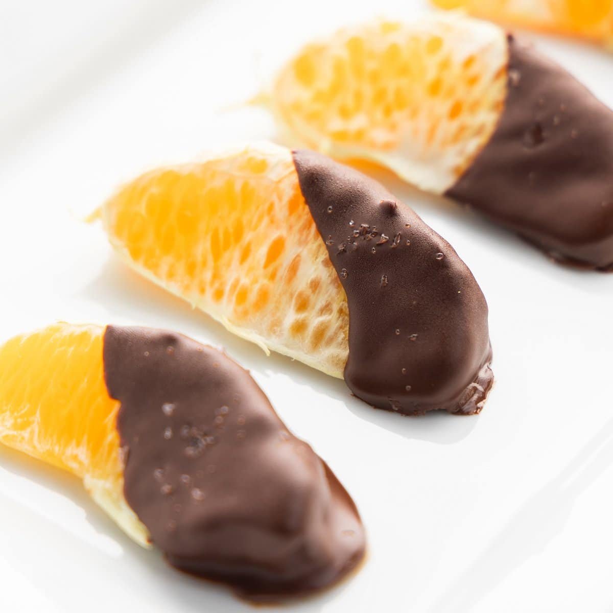 Close up shot of chocolate dipped orange slices sprinkled with sea salt.