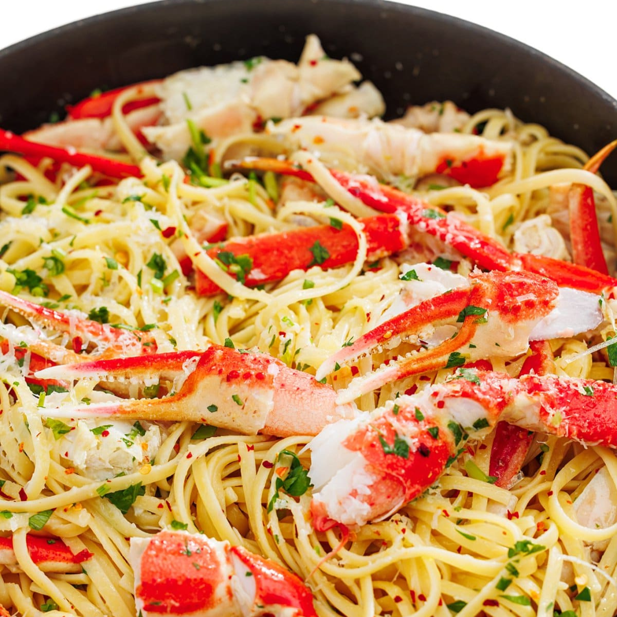 Crab linguine in a white wine garlic sauce garnished with fresh herbs in a large skillet.