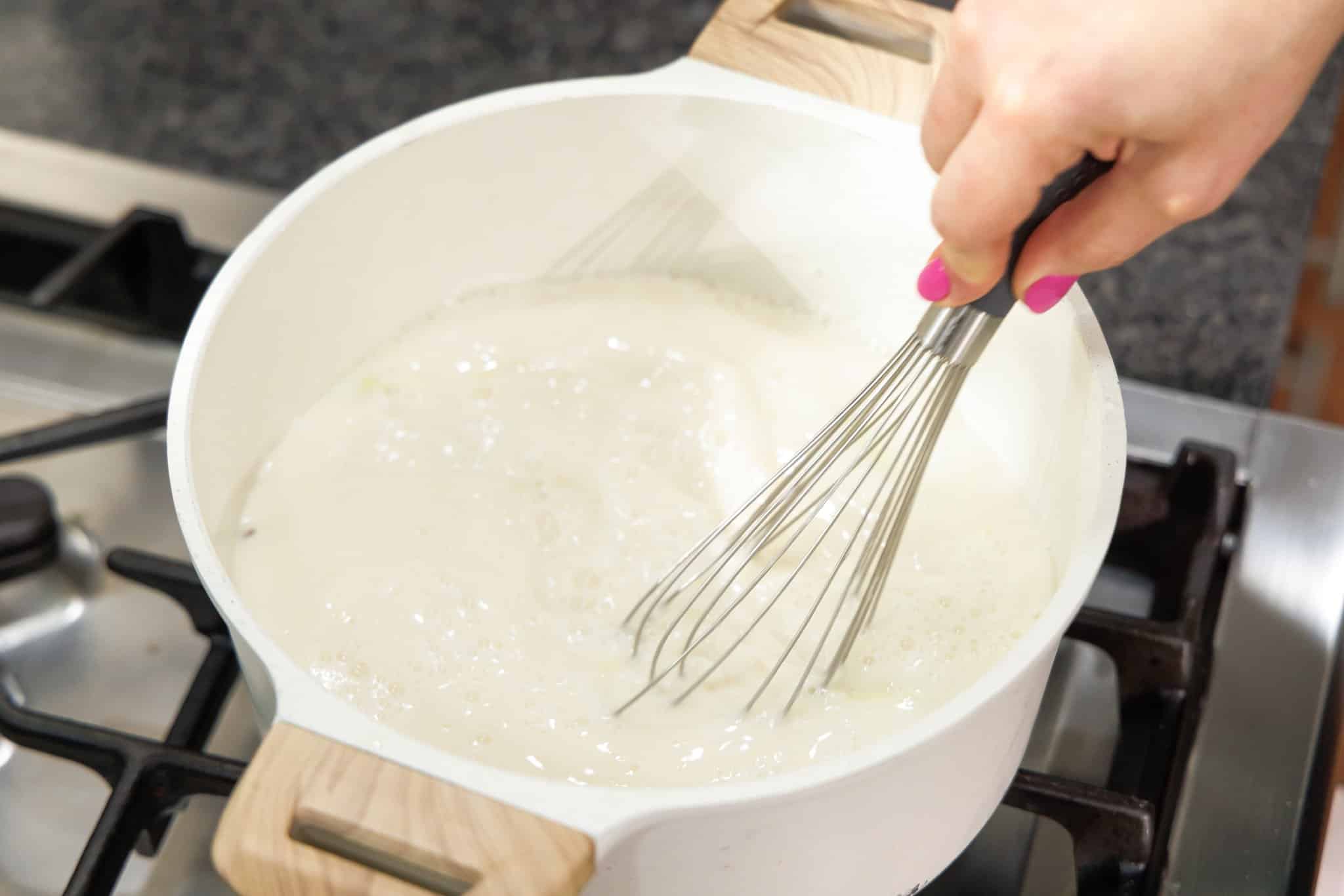 Whisking spices into soup in large pot.