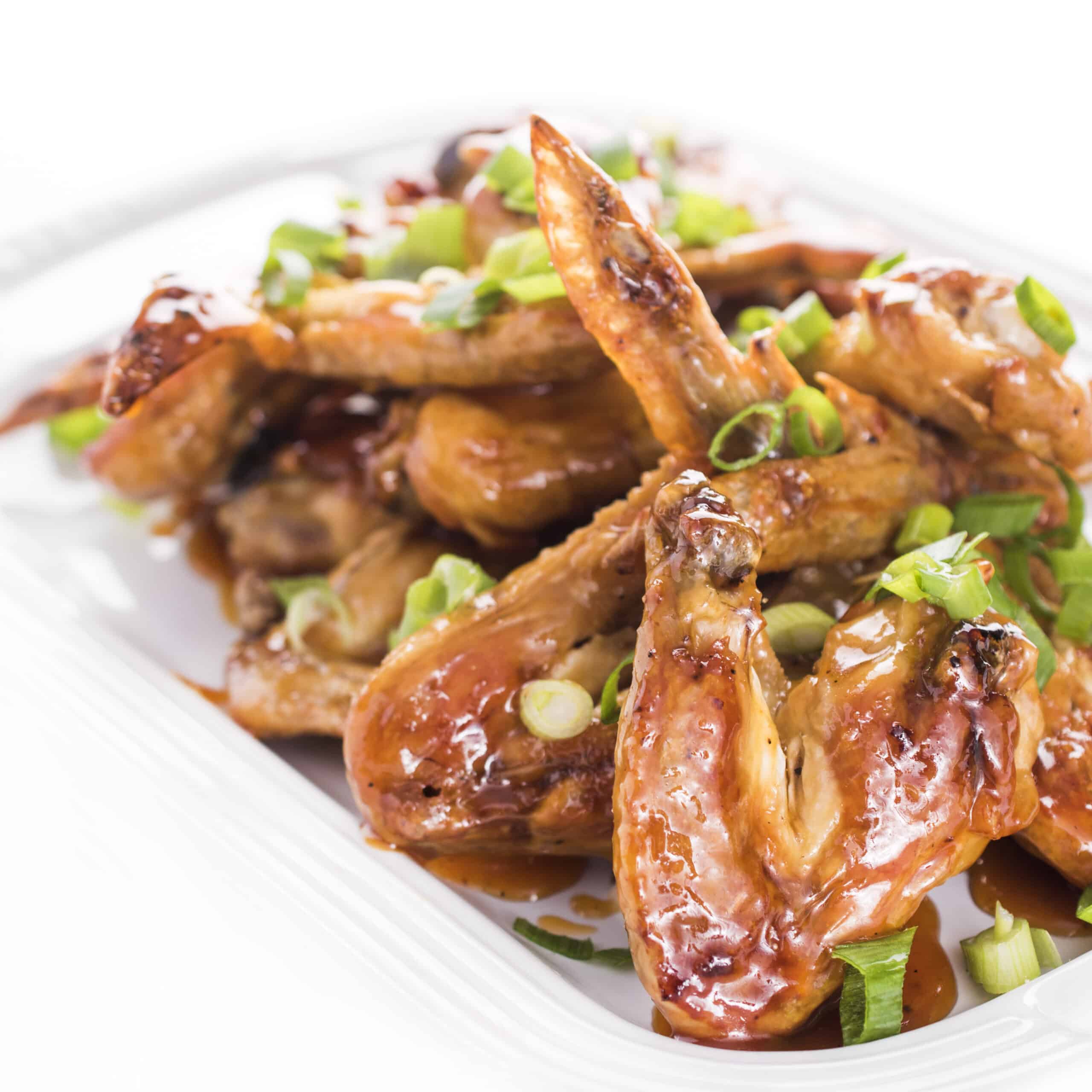 Crispy oven baked chicken wings glazed and garnished with green onions.