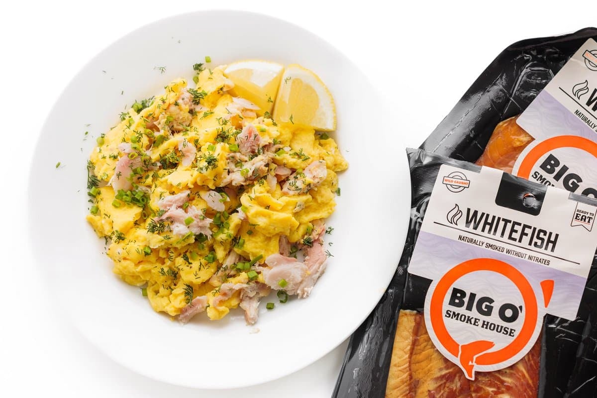 Smoked whitefish egg scramble on a plate next to packages of Big' Smoke House smoked whitefish.