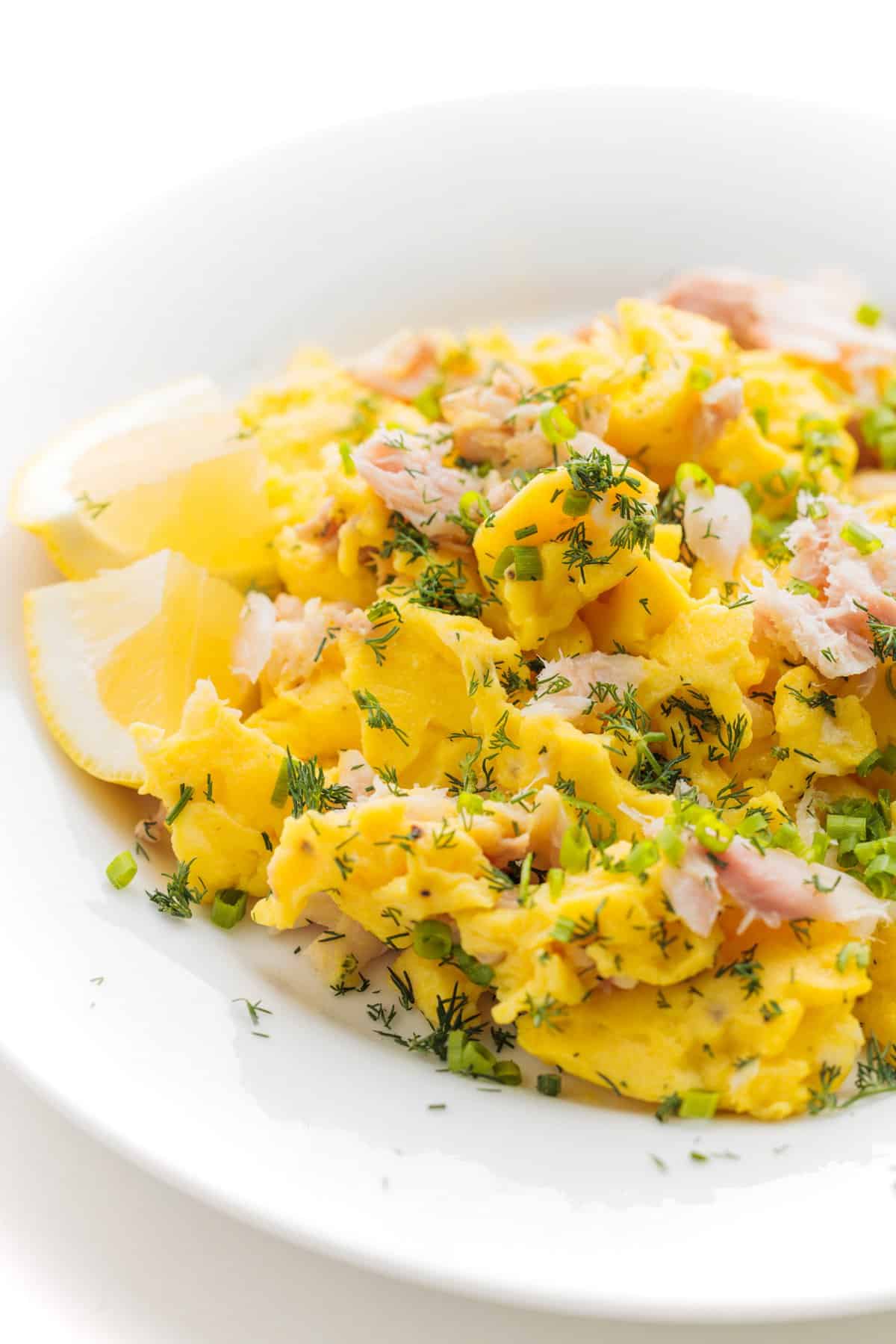 Smoked whitefish egg scramble on a white plate garnished with fresh herbs.
