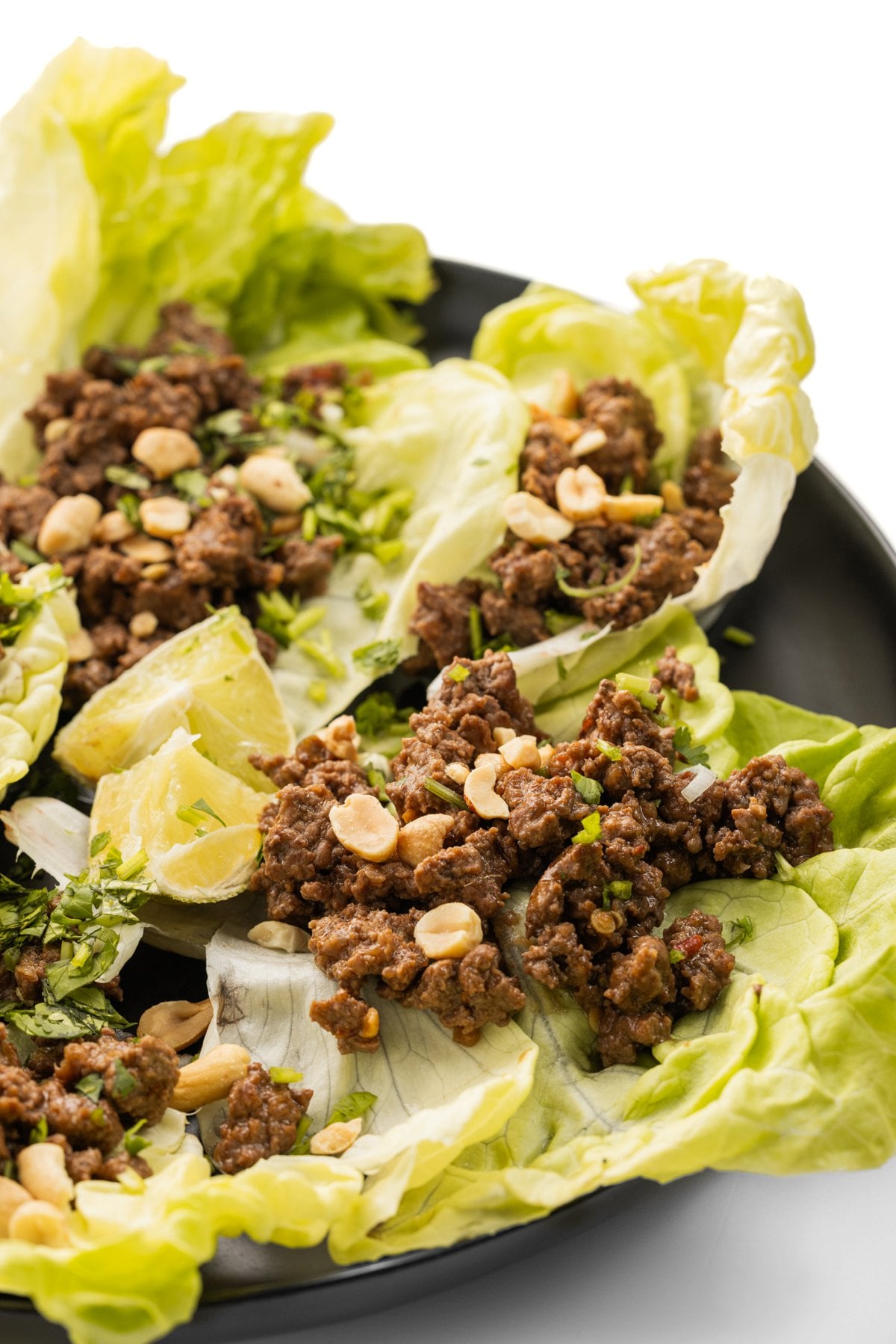 Szechuan beef lettuce wraps garnished with roasted peanuts and fresh herbs.