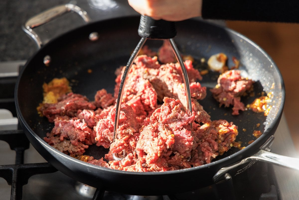 Breaking up ground beef in a skillet.
