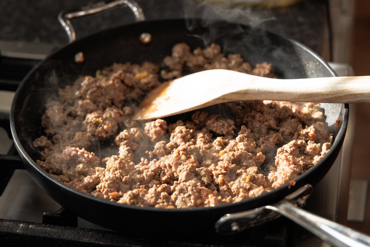 Stirring szechuan beef in skillet.
