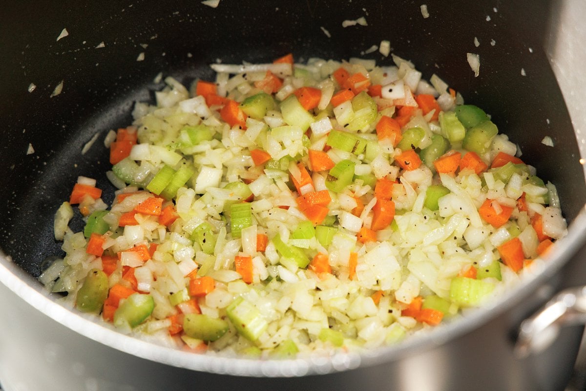Cooking mirepoix in the bottom of a large pot.