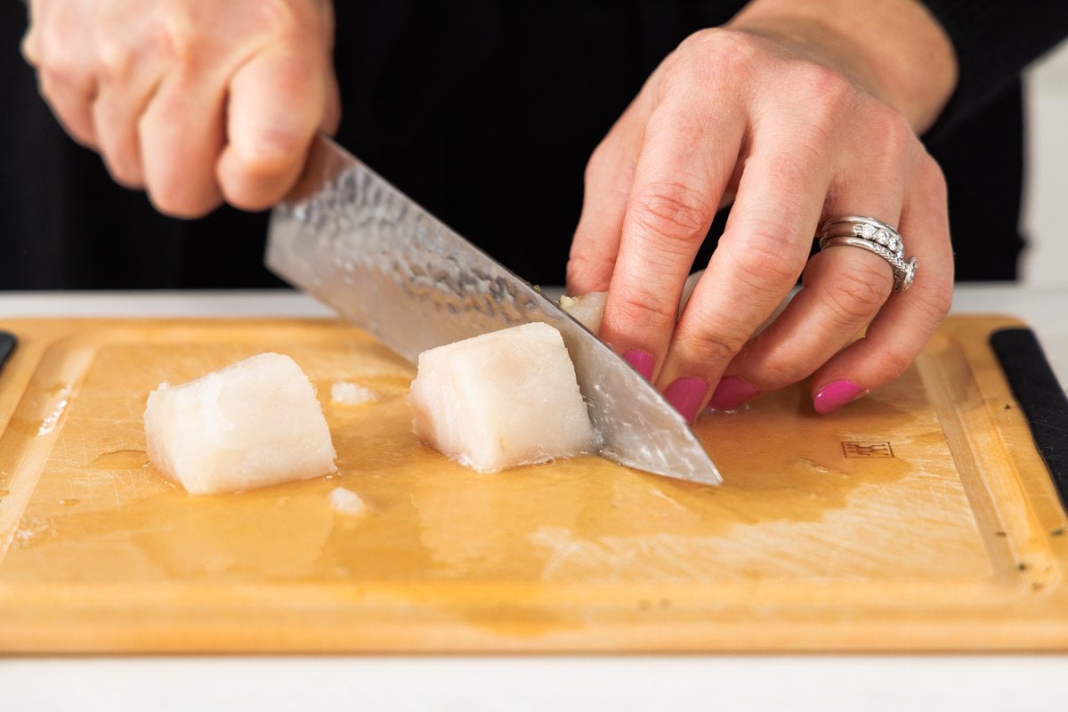 Liz slicing white fish on a cutting board.