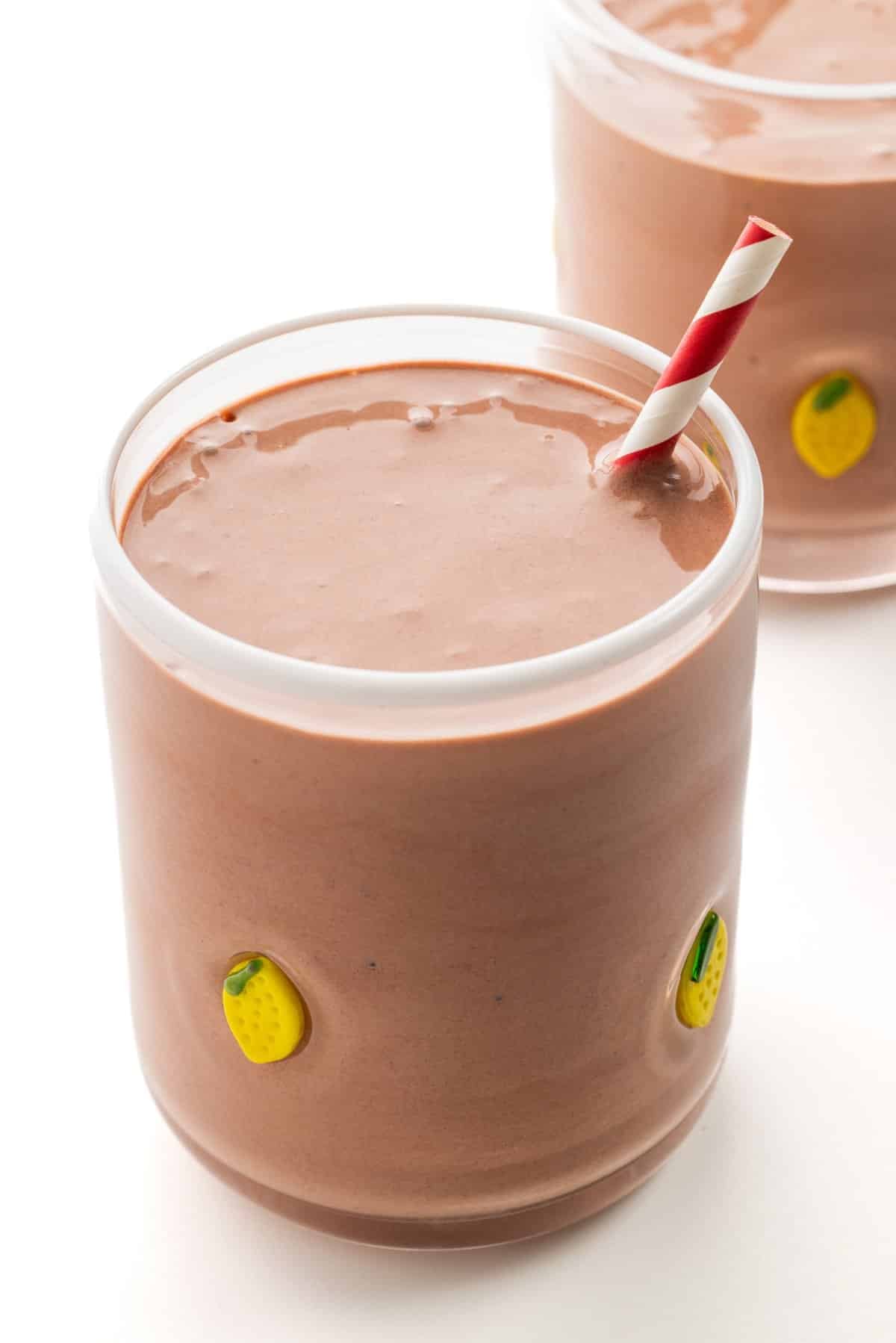Glass tumbler with little lemons on it filled with chocolate cherry protein smoothie.