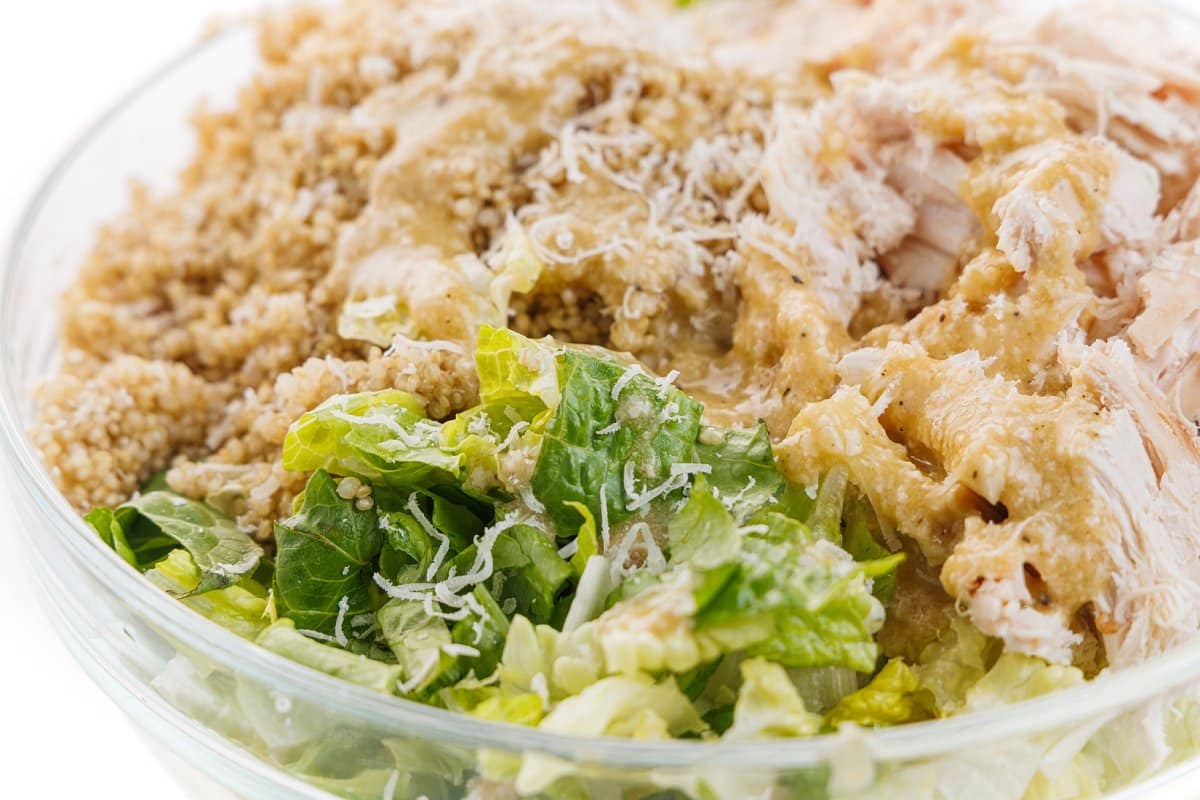 Chicken caesar salad bowl with quinoa topped with shredded parmesan cheese.