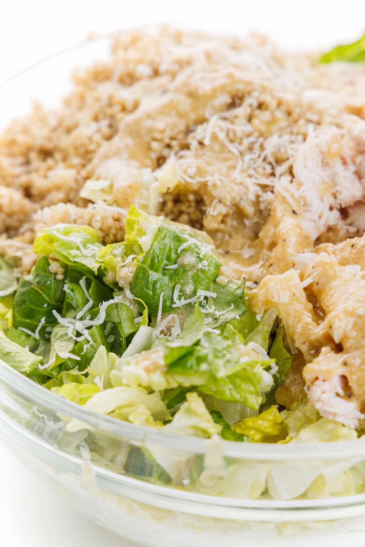 Chicken caesar salad bowl with quinoa topped with freshly grated parmesan cheese.
