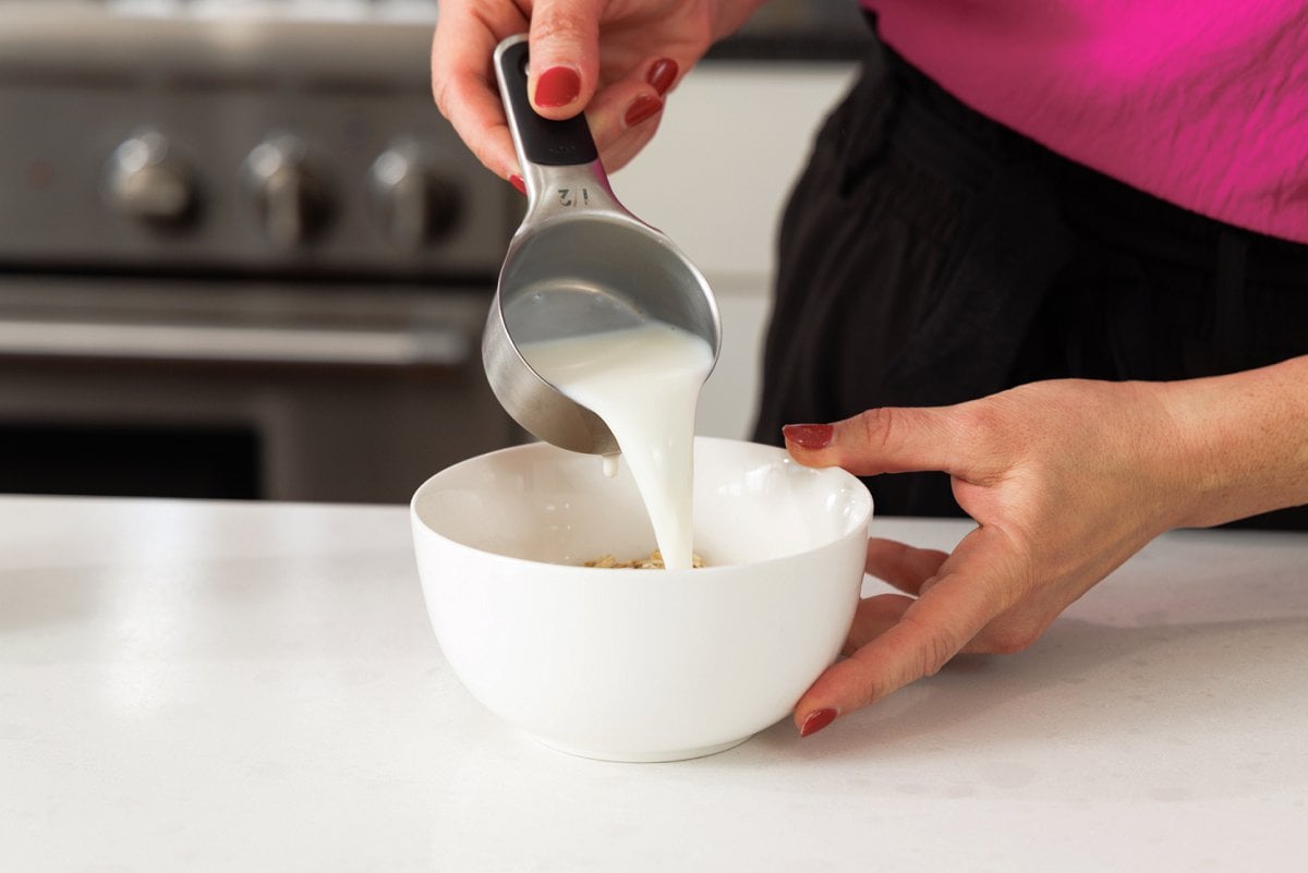 Pouring milk over oats.