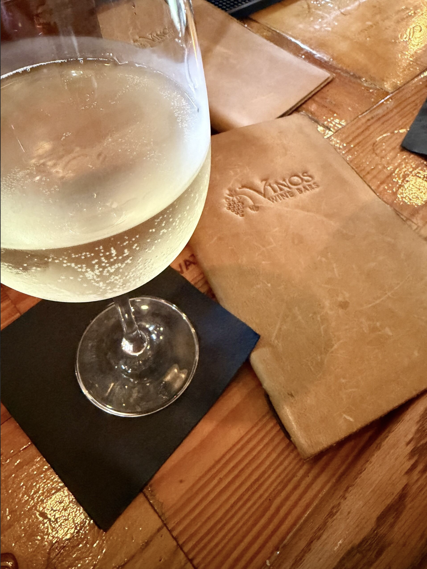 Glass of wine on a napkin next to a wine menu at Vinos wine bar.
