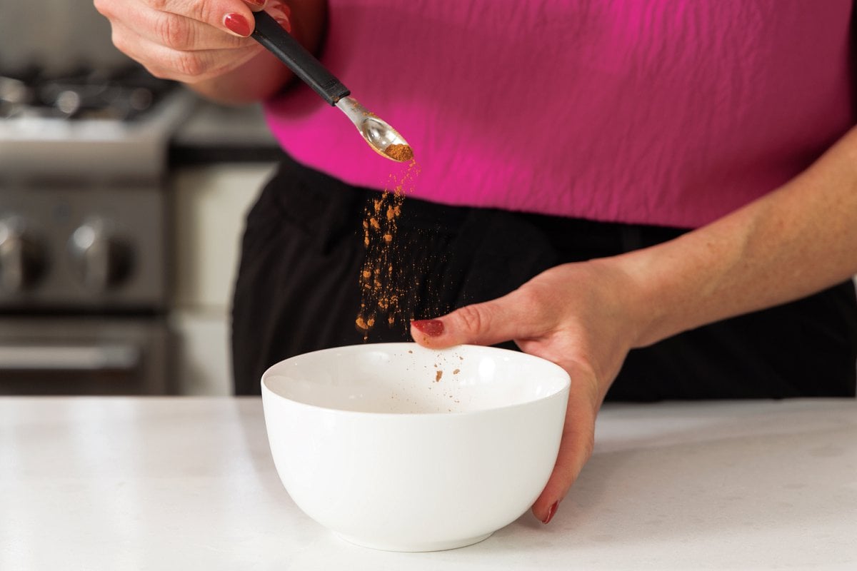 Sprinkling cinnamon into bowl.
