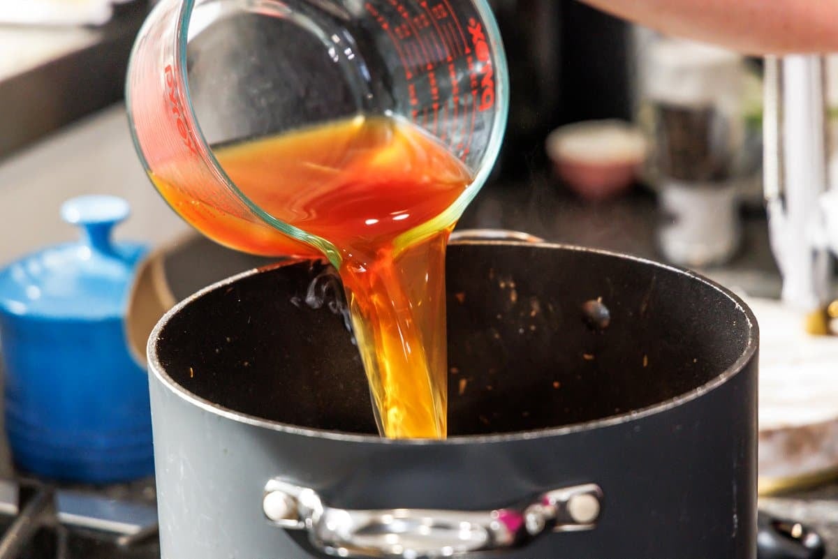 Pouring beef broth into soup pot.