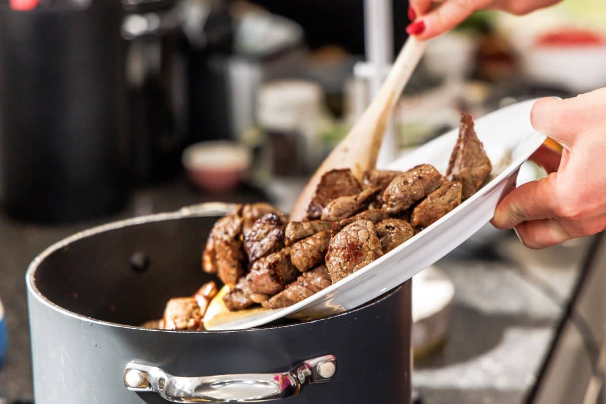 Adding cooked beef to soupl.