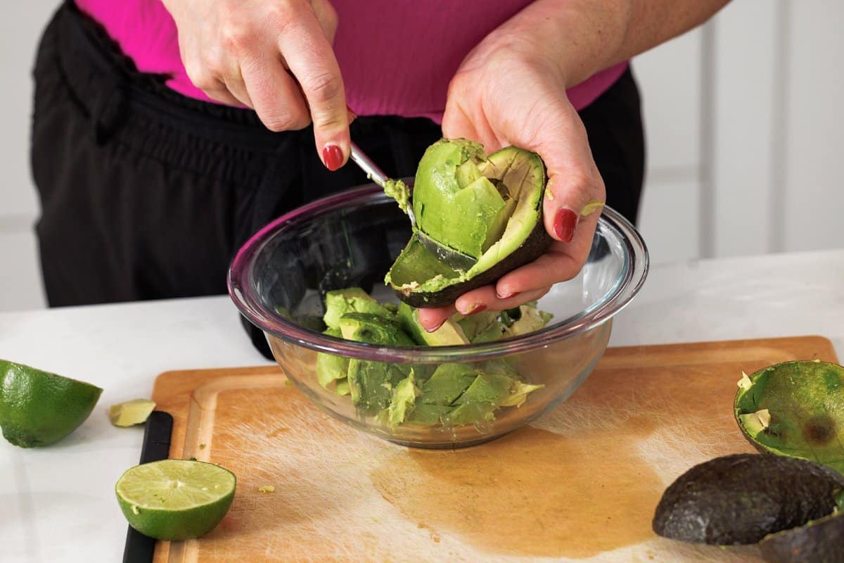 Scooping out avocado into bowl.