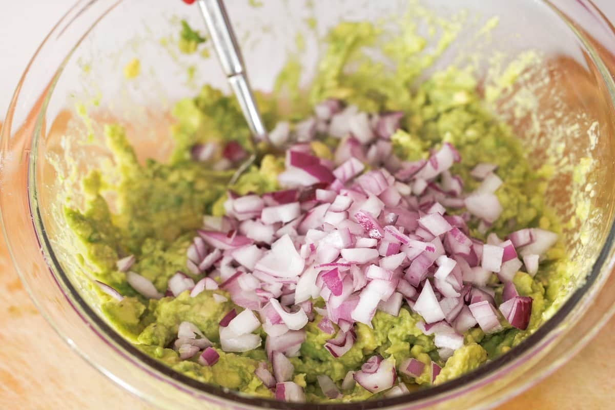 Adding diced red onion to bowl.