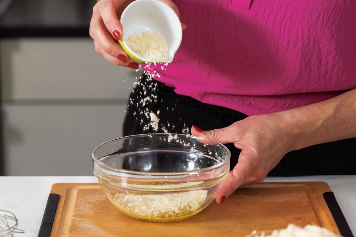 Adding finely grated parmesan cheese to bowl.