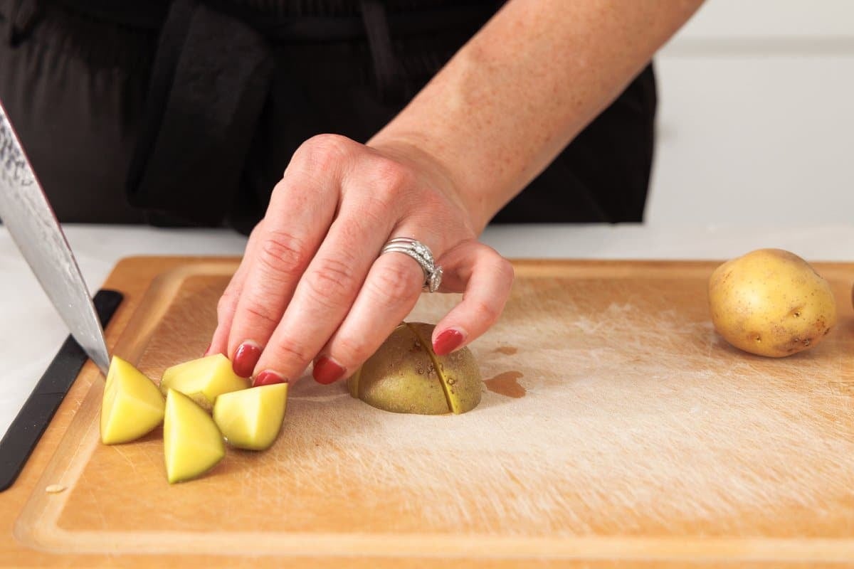 Cutting yukon potatoes into fourths.