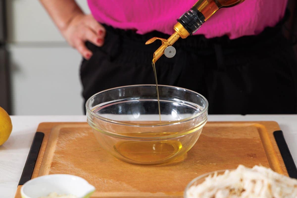 Drizzling olive oil into a glass bowl.