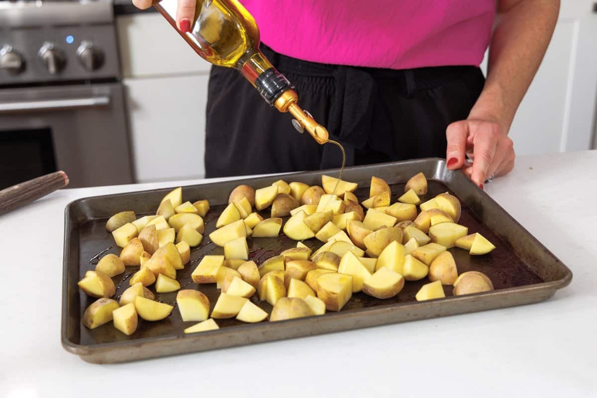Drizzling olive oil over the top of potatoes.