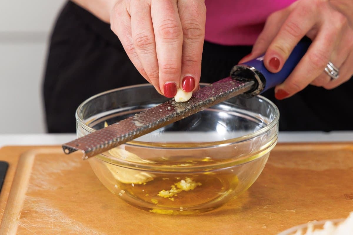 Grating a garlic clove into bowl with a microplane.