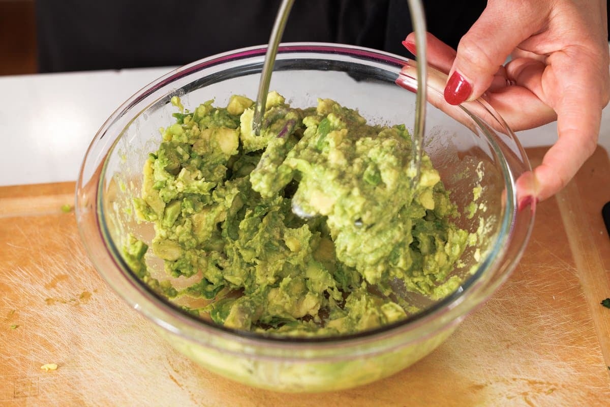 Mashing avocado in glass bowl.