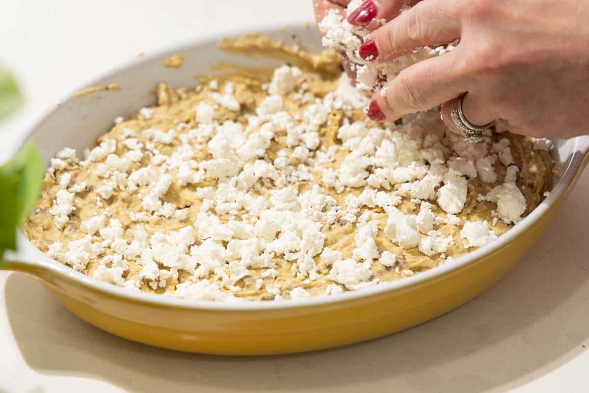 Sprinkling feta cheese on hummus.