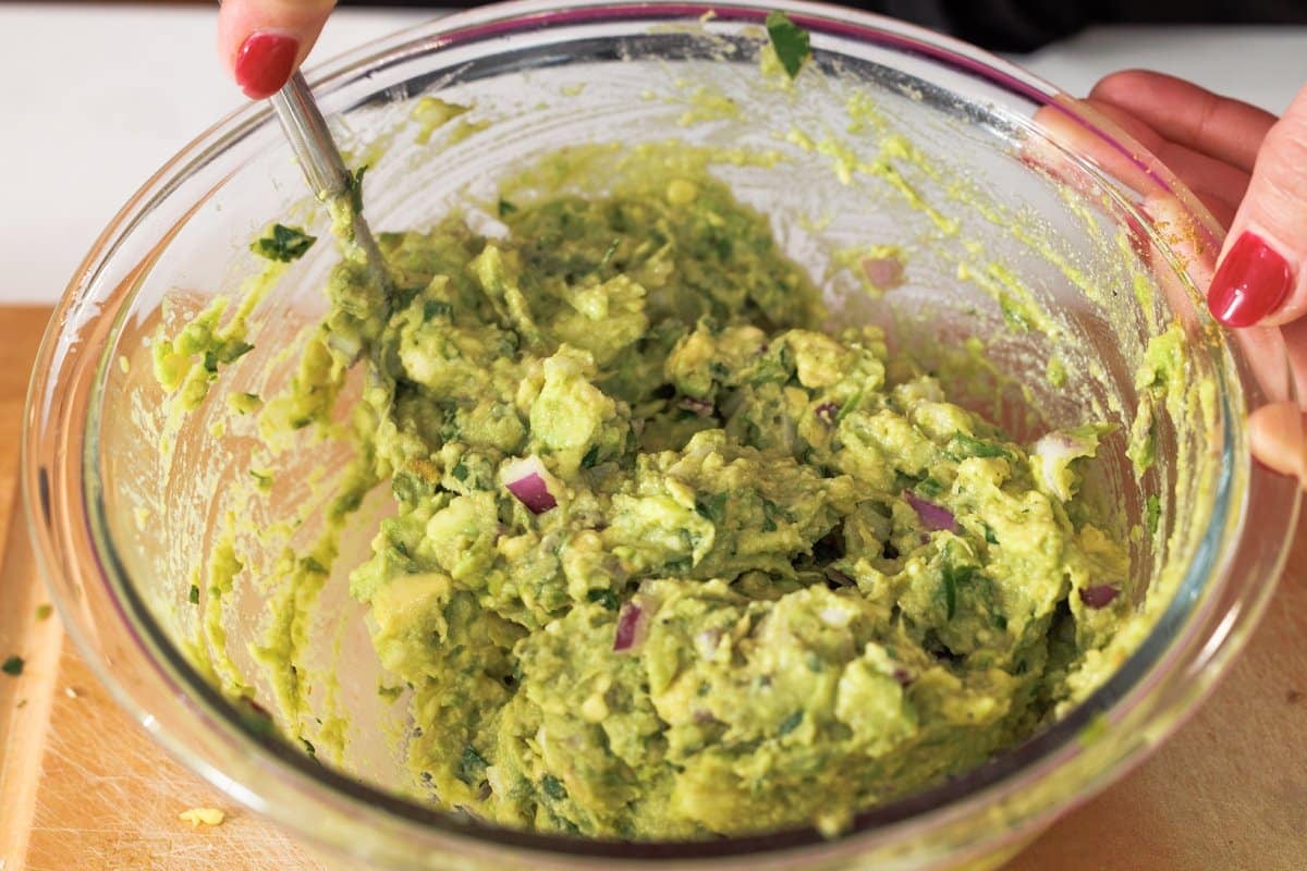 Stirring guacamole in glass bowl.