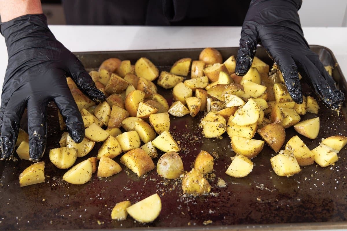Tossing potatoes on baking sheet.