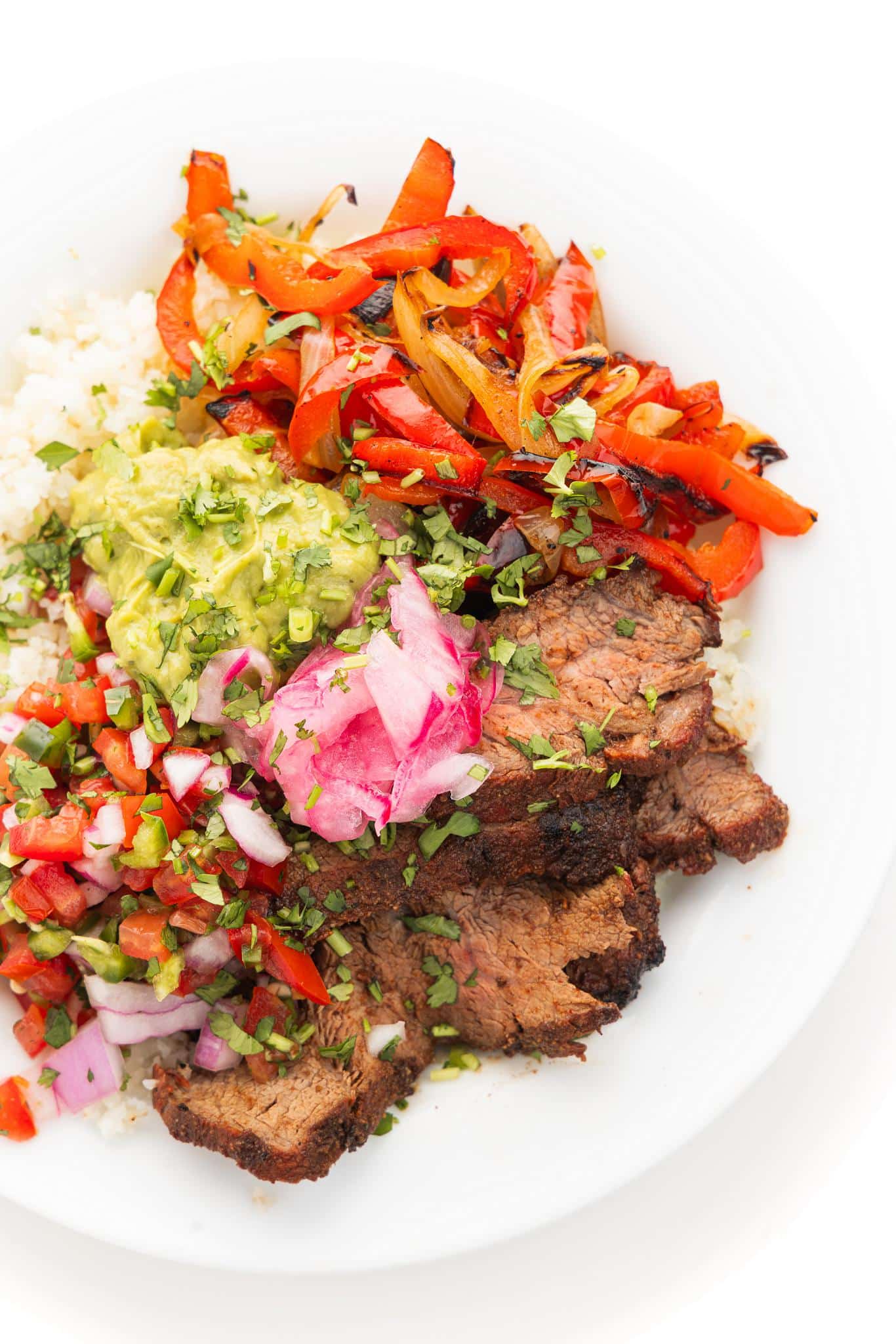 Steak fajita bowl topped with pico and fresh cilantro.