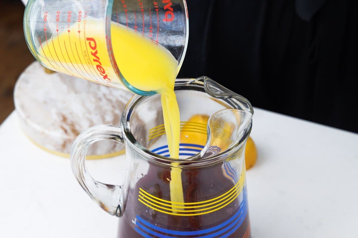 Pouring orange juice into pitcher.