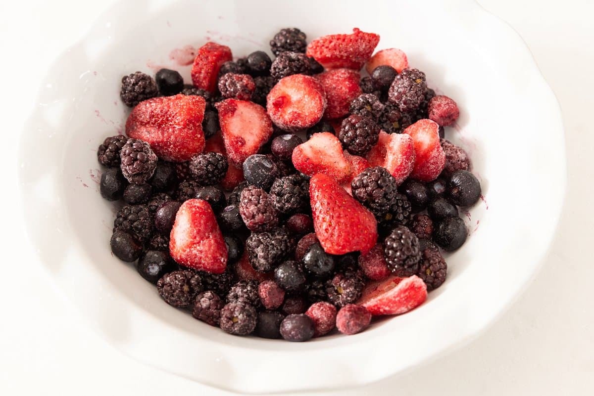 Frozen berries added to pie dish.