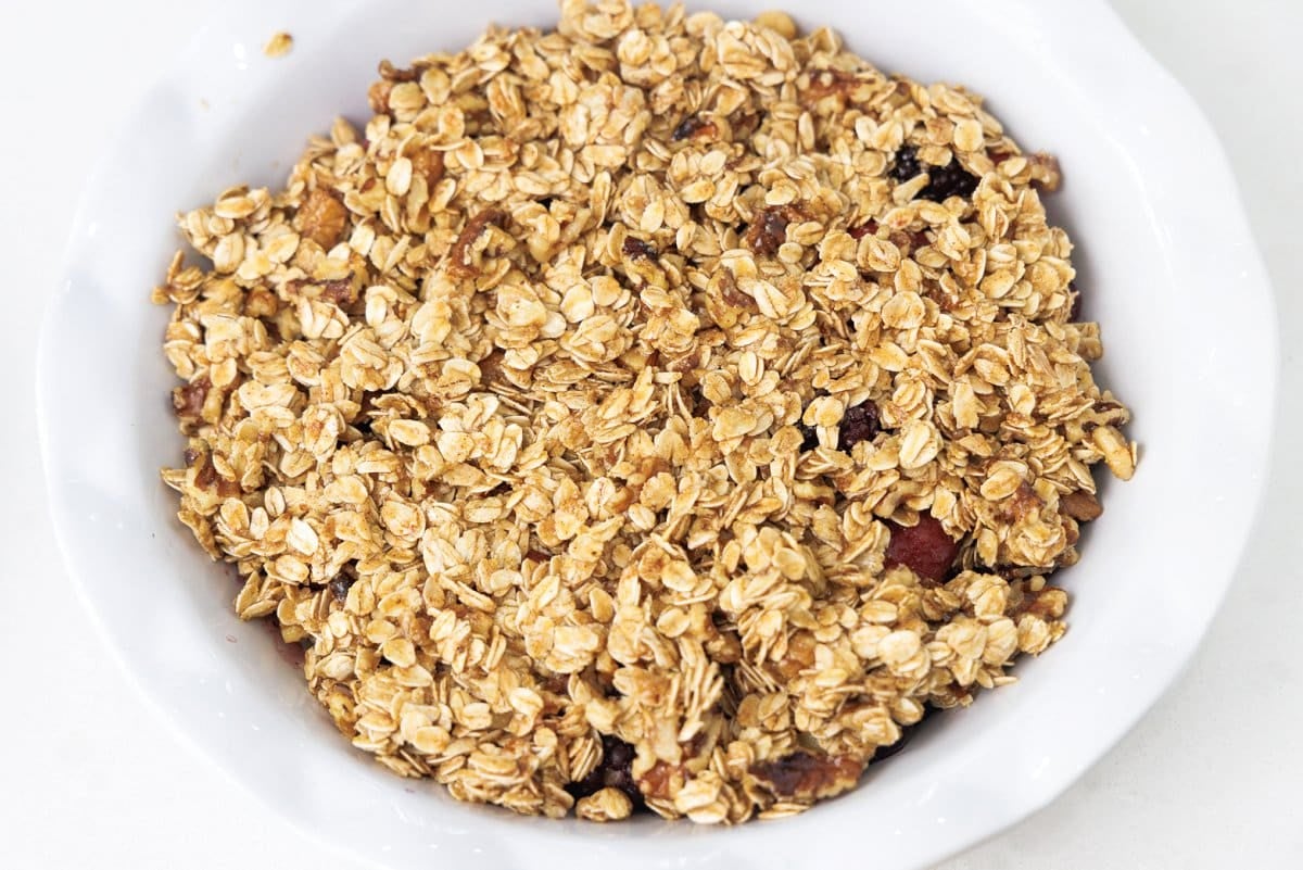 Oat topping mixture on top of berries in pie dish.