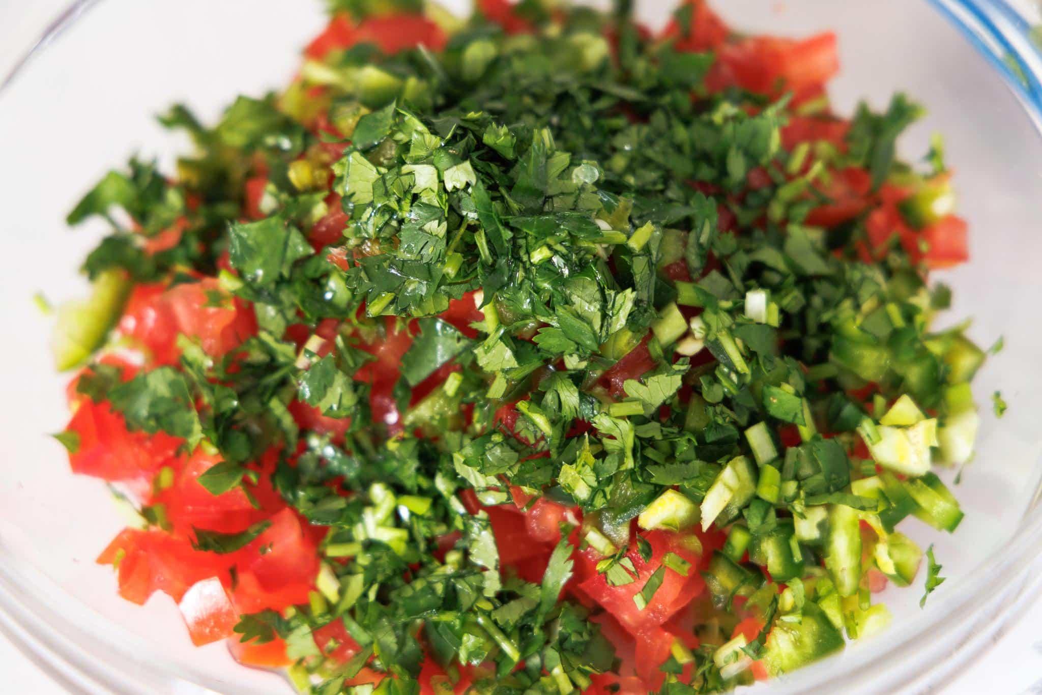 Ingredients for pico de gallo in a glass bowl.