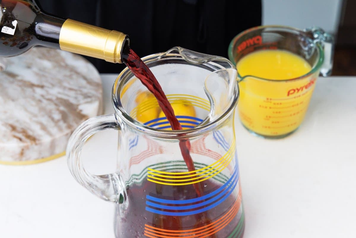 Pouring red wine into a pitcher.