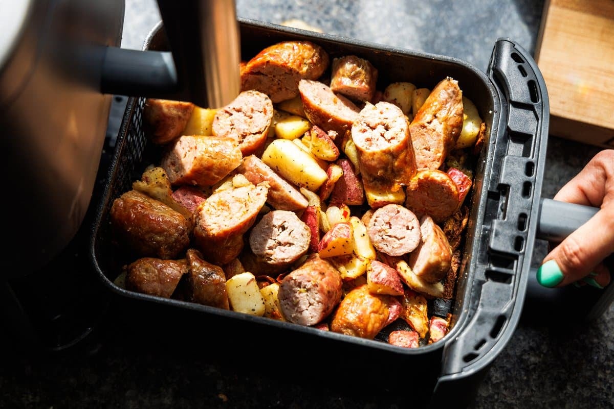 Cut sausage and potatoes, onions, and peppers in an air fryer basket.