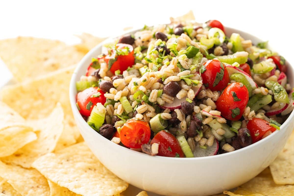 Black bean and barley salad topped with fresh herbs served with chips.