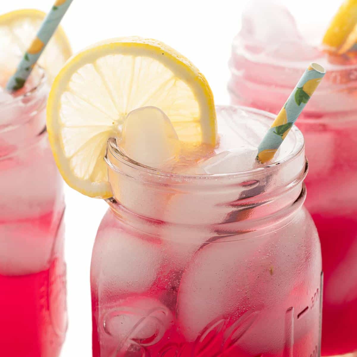 Close up on blueberry vodka lemonade in a mason jar, garnished with a slice of lemon.