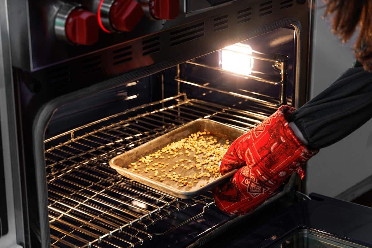 Adding pine nuts to the oven to toast.