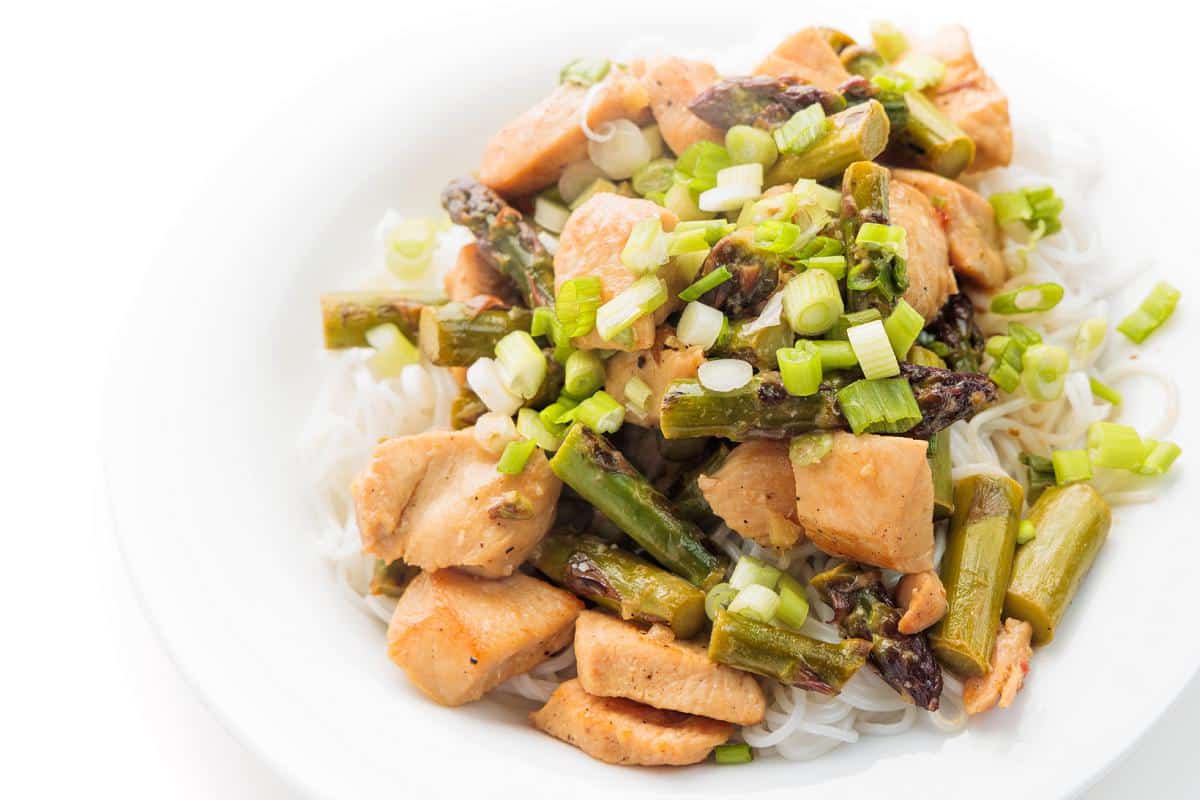 A plate of rice topped with Thai green curry chicken with asparagus.