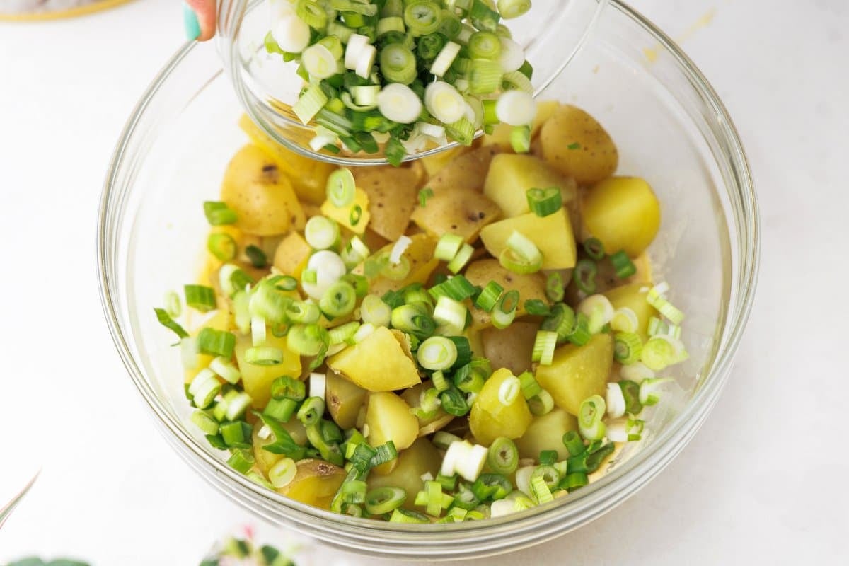 Adding scallions and mint to potatoes.